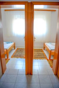 a room with two beds and two windows at Apartmani prvi red do mora in Pag