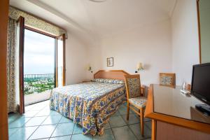 a bedroom with a bed and a tv and a window at La Capannina - Hotel & Apartments in Ischia