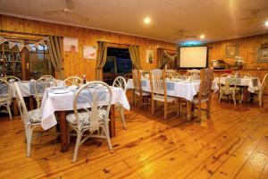 ein Esszimmer mit Tischen, Stühlen und einem Bildschirm in der Unterkunft The Spotted Grunter Resort in Port St Johns