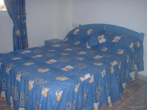 een bed met een blauw dekbed en kussens erop bij Torrevieja, La Torreta Ground Floor Apartment with Large Private Patio Garden in Torrevieja