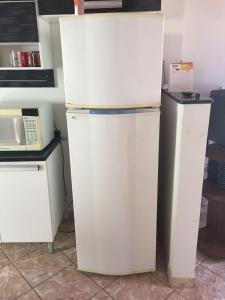 een witte koelkast naast een magnetron bij Casa de praia P Grande in Fundão
