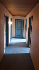 un pasillo vacío con una puerta azul en una habitación en Zimmer vor Sylt und Dänemark, en Klanxbüll