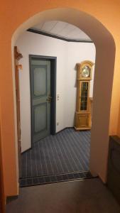 a hallway with a door and a grandfather clock at Zimmer vor Sylt und Dänemark in Klanxbüll