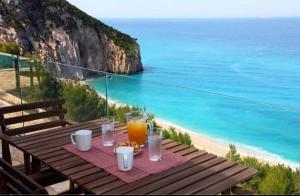 einen Tisch mit einem Teller Essen und Meerblick in der Unterkunft Milos Paradise Luxury Villas in Agios Nikitas