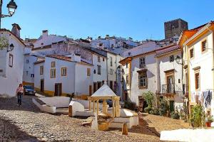 a woman walking down a street in a village at Casa da Avó in Castelo de Vide