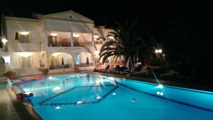 a swimming pool in front of a building at night at Alessandro in Sidari