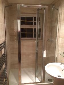 een glazen douche in een badkamer met een wastafel bij Engellie Cottage in Perranporth