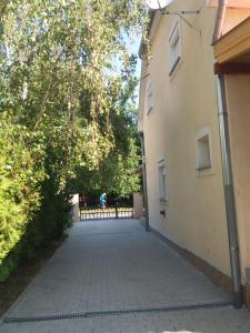 uma passagem entre dois edifícios com árvores e uma cerca em Sommer Ferienhaus em Balatonszárszó