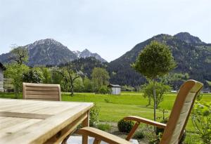 a wooden table and chairs with mountains in the background at Fügenschuhs Genussferien in Bad Hindelang