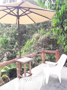 an umbrella and two chairs and a table on a deck at JJ Beach Resort & JJ Seafood in Ko Phayam
