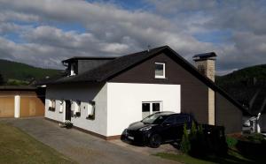 una casa en blanco y negro con un coche aparcado delante en Ferienwohnungen Michel, en Winterberg