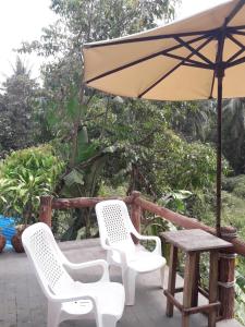 einen Tisch und zwei Stühle und einen Regenschirm auf einer Terrasse in der Unterkunft JJ Beach Resort & JJ Seafood in Ko Phayam