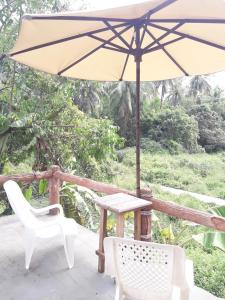 a patio with a table and chairs and an umbrella at JJ Beach Resort & JJ Seafood in Ko Phayam