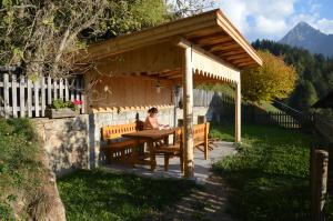 a woman sitting at a picnic table under a pavilion at Ferienwohnung Leachwies in Schenna