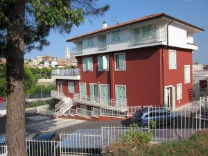 a red house with a white balcony and a tree at Appartamenti I Principi del Conero 2 in Sirolo