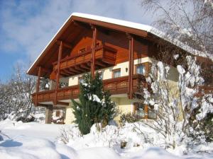 ein großes Holzhaus mit Schnee auf dem Boden in der Unterkunft Ferienwohnungen Haus Bliem in Lieserhofen