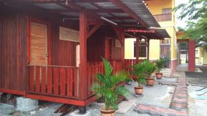 a wooden building with potted plants in front of it at Chalet Kb Wakaf Kayu in Kota Bharu