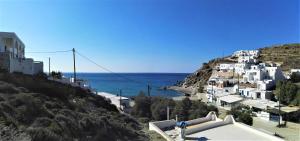 a group of white buildings on a hill next to the ocean at Perigiali Rooms & Apartments Folegandros in Agali