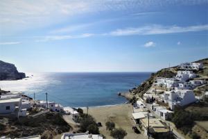 Perigiali Rooms & Apartments Folegandros في Agali: اطلالة على شاطئ به مباني بيضاء والمحيط