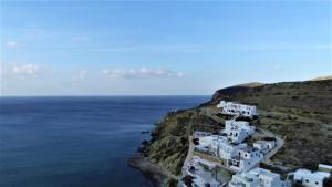 un gruppo di case bianche su una collina vicino all'oceano di Perigiali Rooms & Apartments Folegandros ad Agali