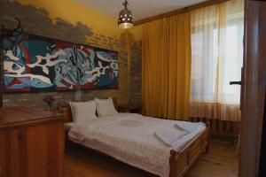 1 dormitorio con 1 cama y una pintura en la pared en Casa de Artes Guest House, en Balchik