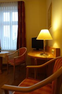 Zimmer mit einem Tisch, einer Lampe und Stühlen in der Unterkunft Pension "Am Nico" in Wernigerode
