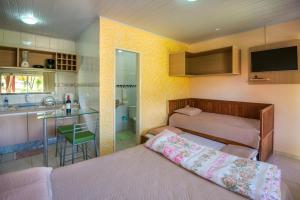 a small bedroom with two beds and a kitchen at Pousada Bela Vista do Capão in Vale do Capao