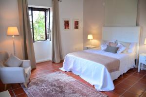 a bedroom with a bed and a chair and a window at Solar Arco de São Jorge in Santana