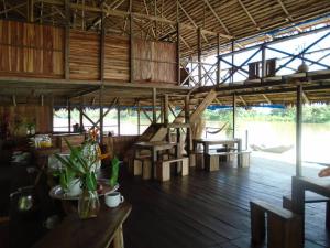 Habitación grande con suelo de madera, mesas y sillas. en Cabaña Flotante Kurupira, en Leticia