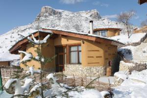 a house covered in snow with a mountain in the background at Eco Village Under the Cliffs in Ilindentsi