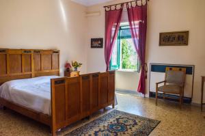 1 dormitorio con cama, ventana y silla en Affascinante Villa Ottocentesca a Caltagirone en Caltagirone