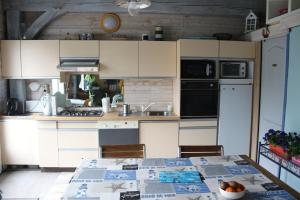 a kitchen with white cabinets and a table at Le Ch'tipanier in Morcenx