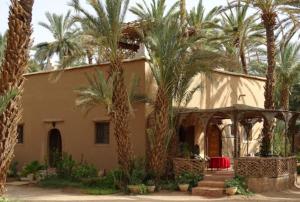 une maison avec des palmiers devant elle dans l'établissement Dar Jnane - La Maison Du Jardin, à Agdz