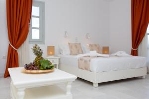 a white bedroom with two beds and a table at Sun and Moon Villas in Aliko Beach