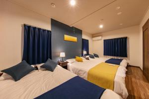 2 łóżka w pokoju z niebieskimi zasłonami w obiekcie Kyoan Shion w mieście Kioto