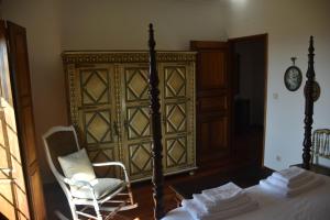 a bedroom with a bed and a chair and a clock at Quinta do Bacelo, Casa completa, 4 quartos e piscina in Braga