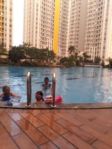 drie personen in een zwembad in een stad bij Apartemen Springlake Summarecon Bekasi-By Bu Johan in Bekasi
