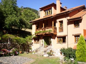 a house with a balcony on a hill at Apartamentos Rurales Buenamadre in Pola de Somiedo