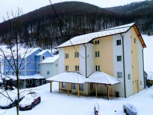 a building covered in snow with cars parked in the snow at Vila Vuk Wolf in Brzeće