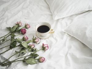 eine Tasse Kaffee und rosa Rosen auf dem Bett in der Unterkunft Gemütliches, heimeliges Ferienhaus in Gars am Kamp