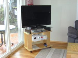 einen Flachbild-TV auf einem Holzständer im Wohnzimmer in der Unterkunft Am Ringwall 76 in Cuxhaven