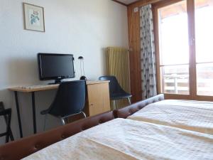 Schlafzimmer mit einem Bett und einem Schreibtisch mit einem TV in der Unterkunft Hotel Bellevue in Heiligenschwendi