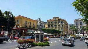 Una calle de la ciudad con coches y una estatua en el medio en Casa Fortuna, en Sorrento