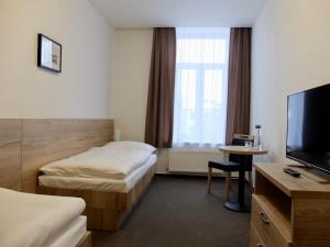 a hotel room with two beds and a flat screen tv at Penzion Stará pošta in Frýdek-Místek