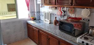 a kitchen counter with a microwave and a sink at Jolie appartement vue mer in M'diq