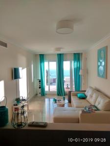 uma sala de estar com um sofá branco e cortinas azuis em Manilva Playa em Manilva