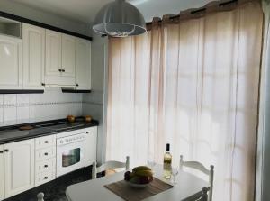 una cocina con armarios blancos y una mesa con una botella de vino en Alojamiento San Antonio, en Valle Gran Rey