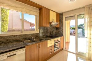 ロダ・デ・バラにあるCasa Montse Baràの木製のキャビネットとシンクと窓のあるキッチン