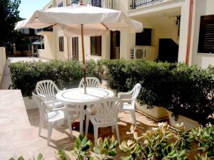 a white table and chairs with an umbrella at Casa Vacanze Metrosideros in San Vito lo Capo