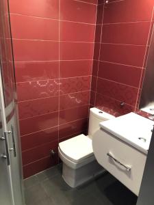 baño con aseo y pared de azulejos rojos en Avenida de las Piletas, en Sanlúcar de Barrameda